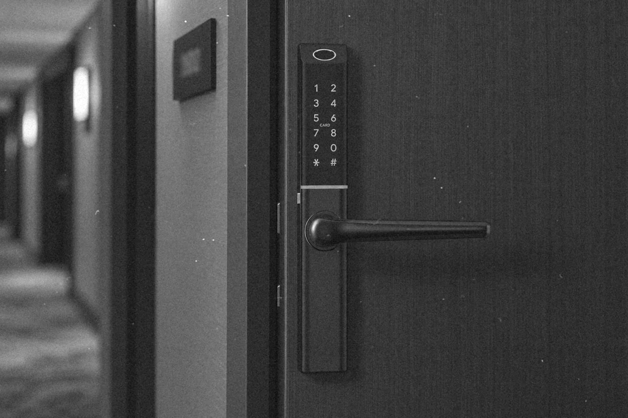 Elektroniczna klamka TTLock w drzwiach pokoju w aparthotelu, obok recepcja bez kolejki