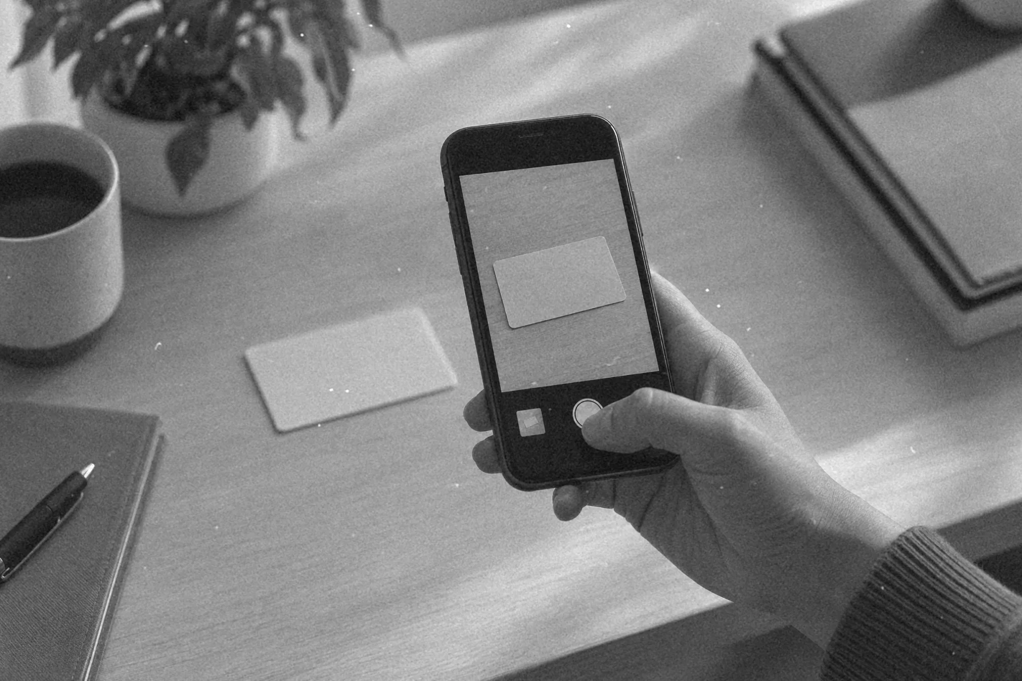 Dłoń trzyma smartfon nad kartą bezpieczeństwa i robi jej zdjęcie na biurku