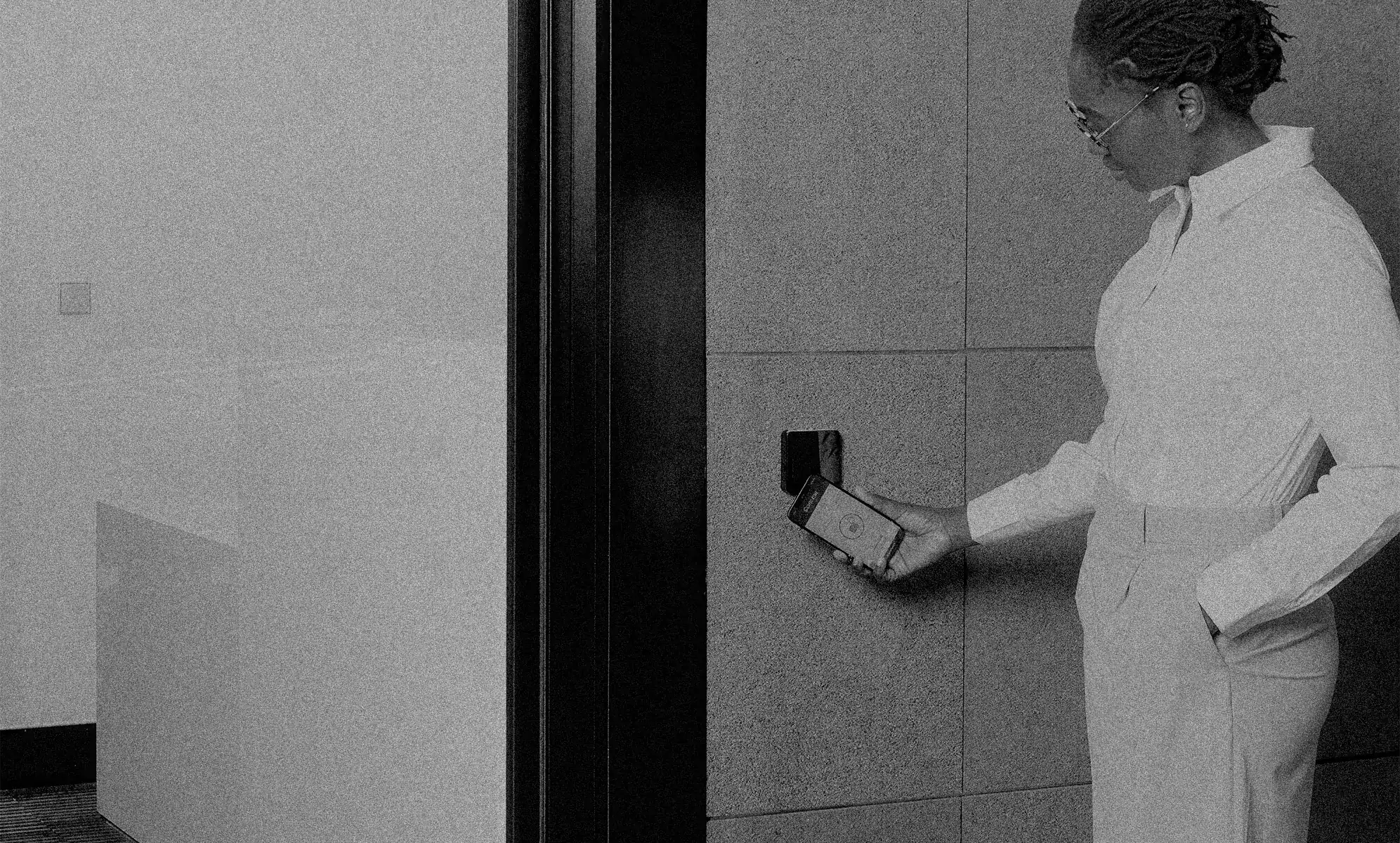 Kobieta otwiera drzwi biura telefonem przy czytniku SMARTair