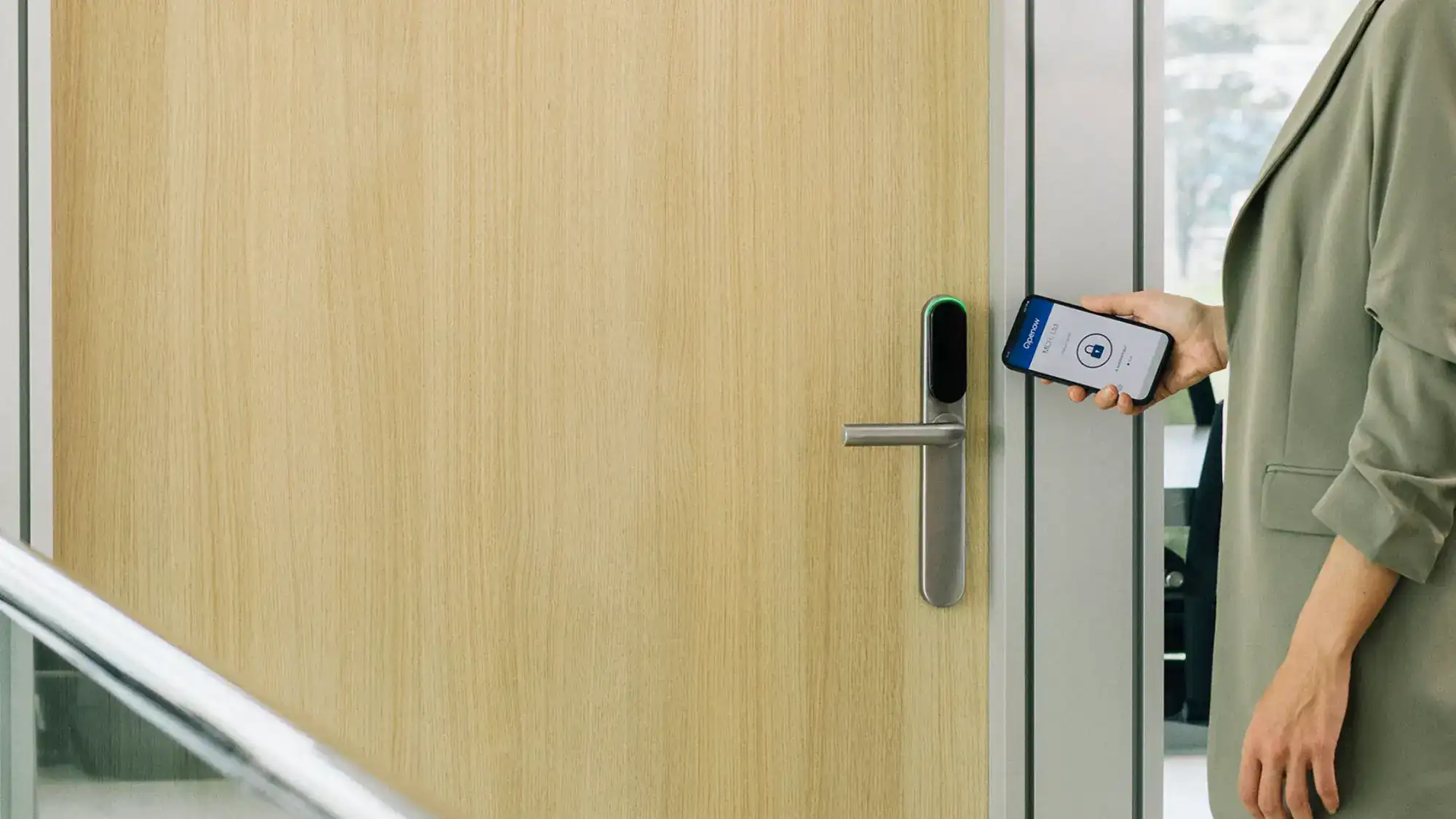 Kobieta otwiera drzwi biura telefonem przy okuciu elektronicznym SMARTair