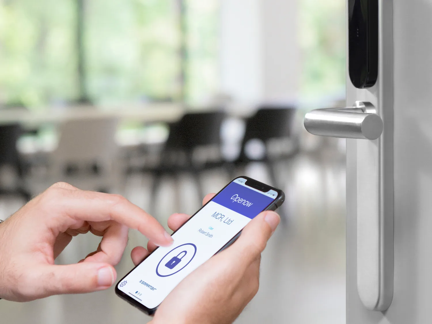 Okucie elektroniczne SMARTair na drzwiach biura, obok telefon z aplikacją